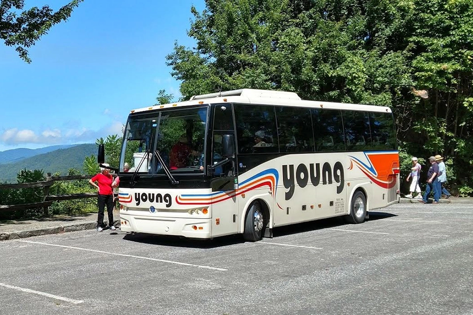 Passengers boarding a Young Transportation 36-passenger motorcoach at a mountain overlook