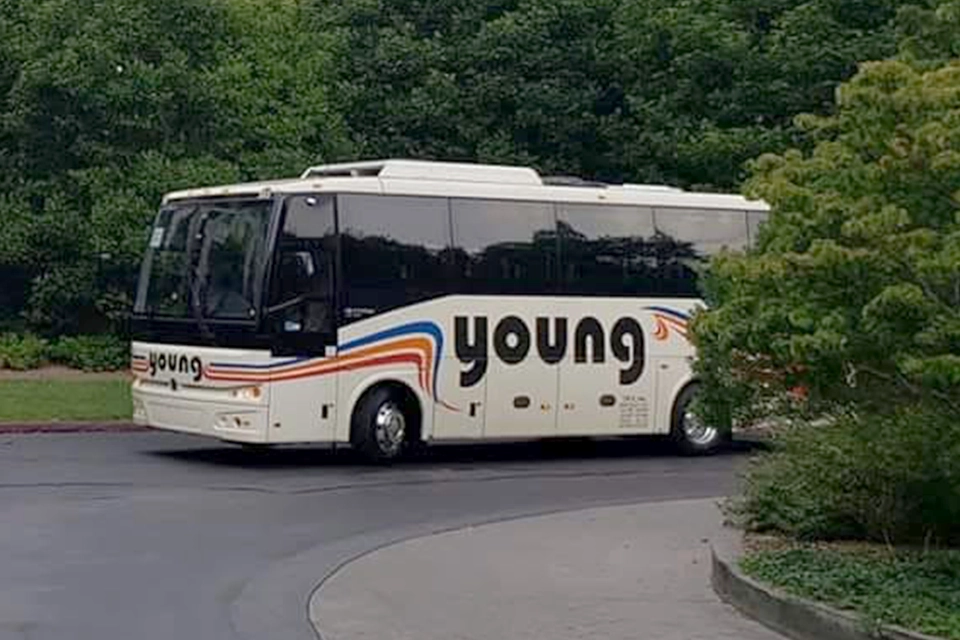Young Transportation 36-passenger motorcoach on a curved drive lined with trees