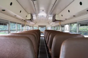 Interior aisle of a Young Transportation activity bus with brown bench seating