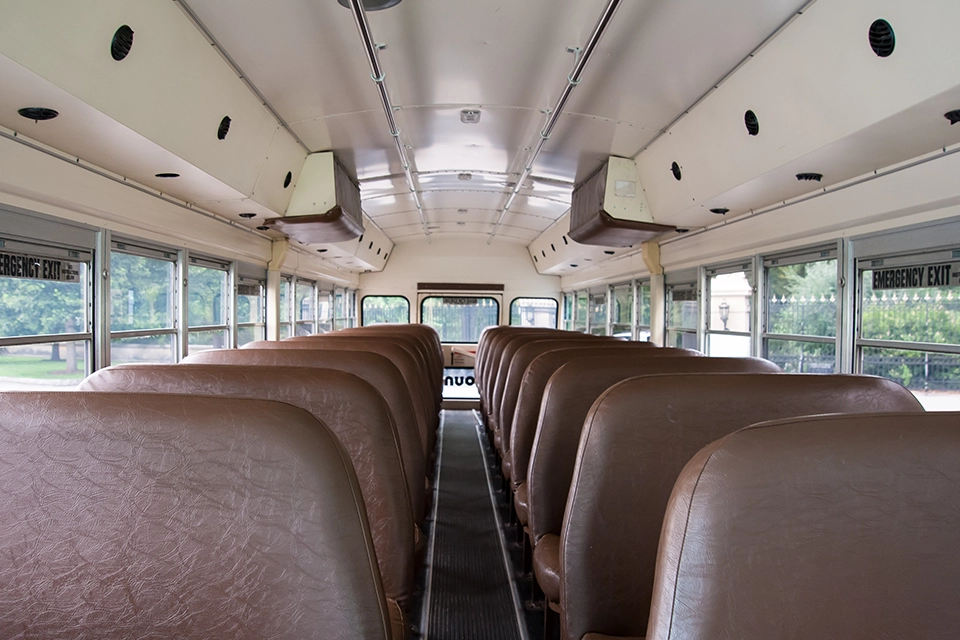 Interior aisle of a Young Transportation activity bus with brown bench seating