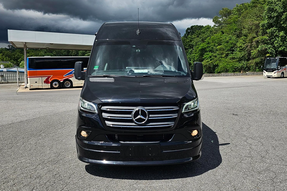 Young Transportation luxury van, front view, parked with motorcoaches behind