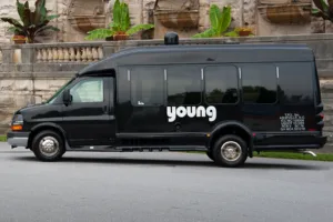 Young Transportation branded black passenger van parked outside a stone building