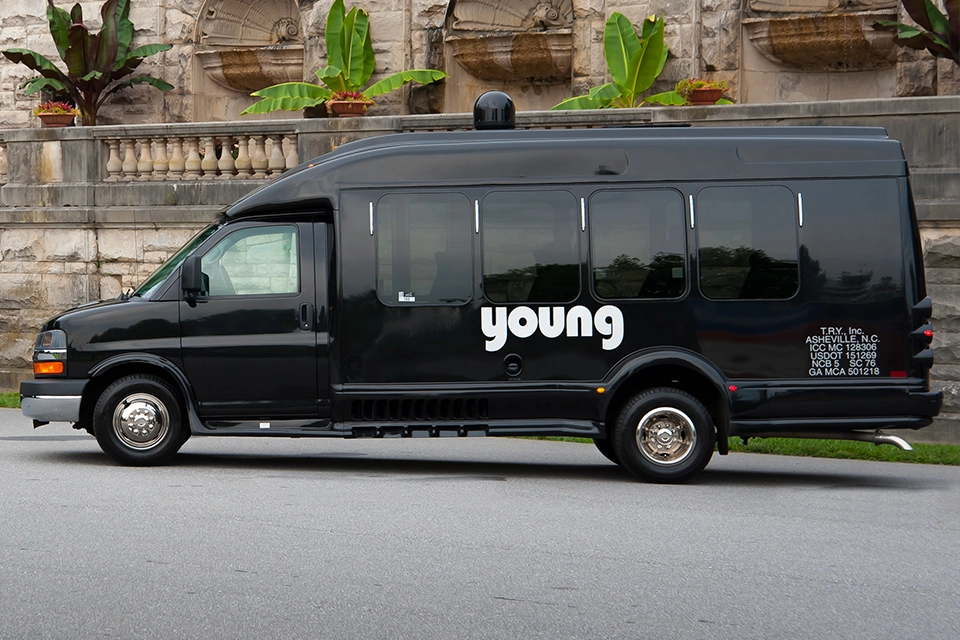 Young Transportation branded black passenger van parked outside a stone building