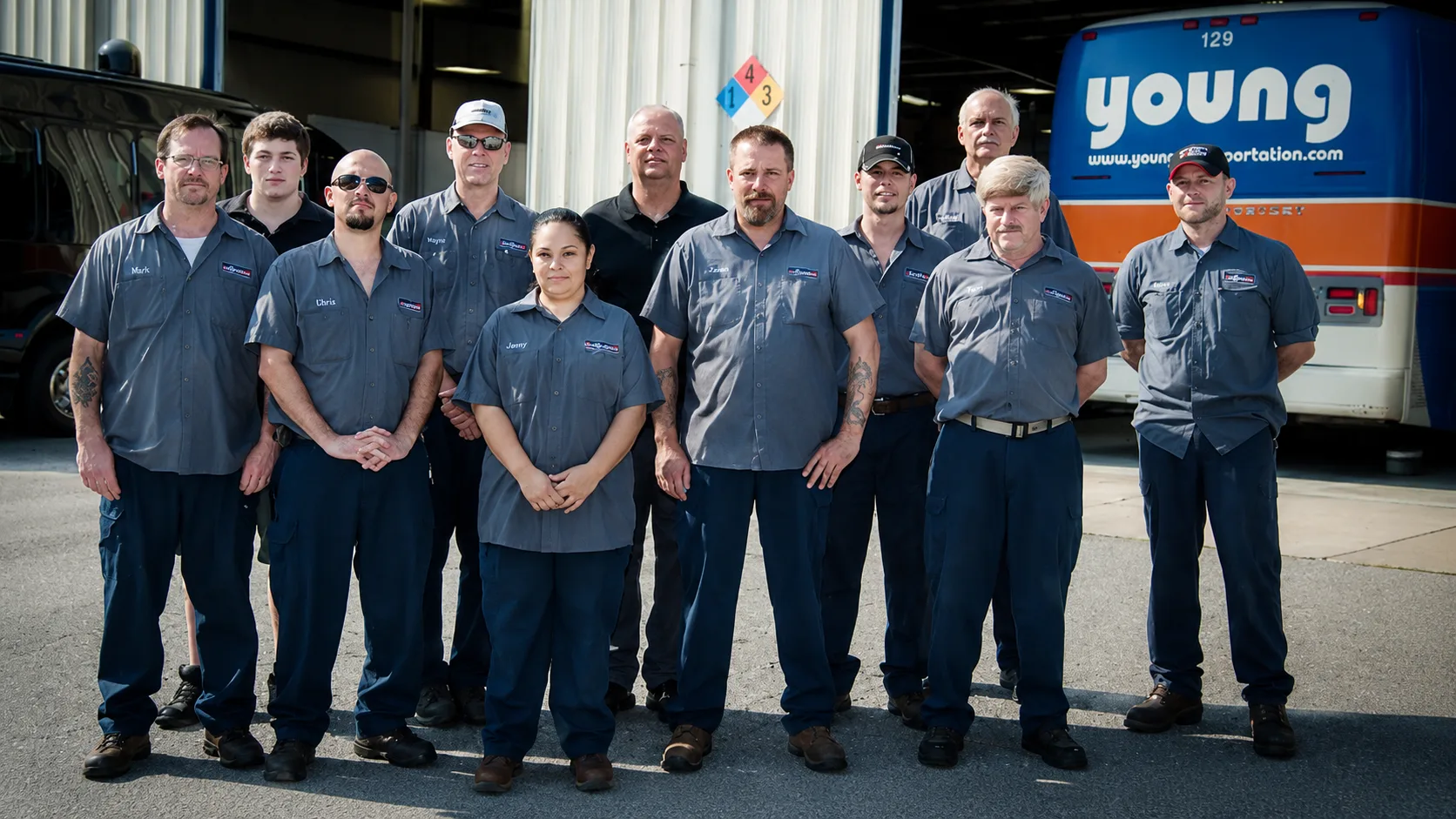 Young Transportation maintenance technicians standing together in front of a motorcoach
